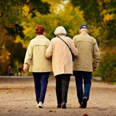 Elderly Woman Maintaining Balance by Holding Onto her Elderly Female and Male Friends' Arms
