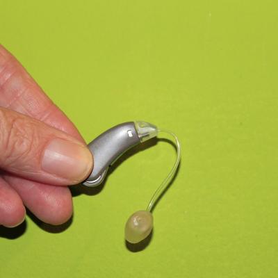 Hand Holding a BTE Hearing Aid with Tube and Dome