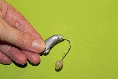 Hand Holding a BTE Hearing Aid with Tube and Dome